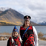 Une mère et son enfant portant des vêtements traditionnels du clan des orques, debout devant une rivière.