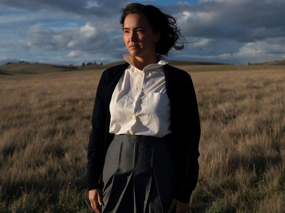 Actor Grace Doyle, in character as Aline Spears, standing in a field.