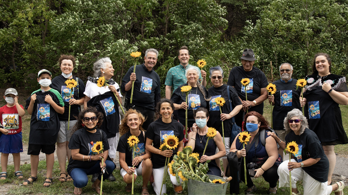 Group of Wisdom Mural Indigenous and community volunteers holding sunflowers, which are featured in the mural