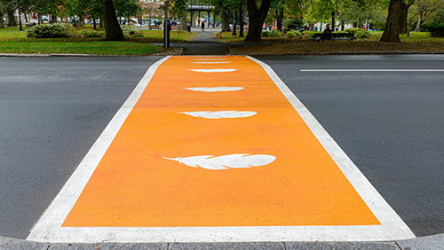 Passage piéton peint en orange avec des plumes blanches