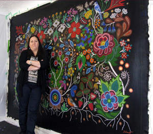 L'artiste métisse Christi Belcourt se tient devant son tableau intitulé « This Painting is a Mirror » [Ce tableau est un miroir].