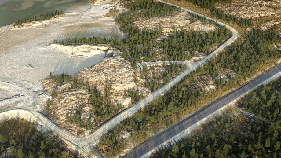 Illustration aérienne d'une zone d'emprunt potentielle sur le site de la mine Giant. Les résidus sont visibles sur le côté gauche de la photo. Un chemin de terre passe entre l'affleurement et les arbres au milieu de la photo, et une route asphaltée bordée d'arbres de chaque côté est visible sur le côté droit de la photo.