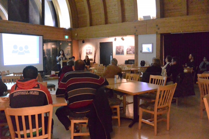 La photo montre l'experte-conseil de CanNorth Stacey Fernandes présentant les résultats de l'ERSHE. Des résidents de Yellowknife assistent à la présentation au Café du Musée. 
