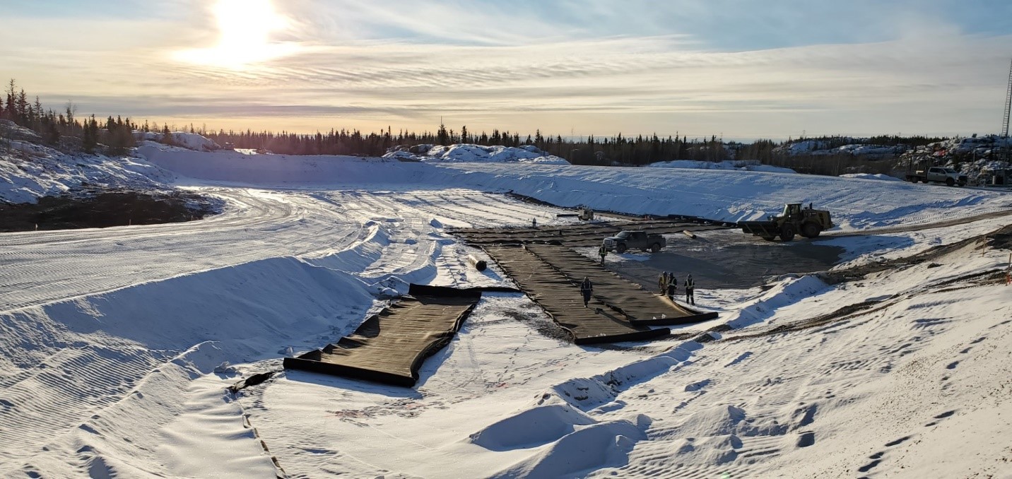 Travailleurs qui relient des sections de la membrane au fond de la décharge de déchets non dangereux.